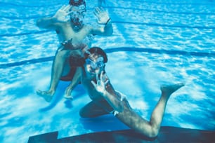 Divertimento subacqueo. Bambina carina con occhialini che nuota sott'acqua e si tuffa nel sondaggio di nuoto. Sport e tempo libero.