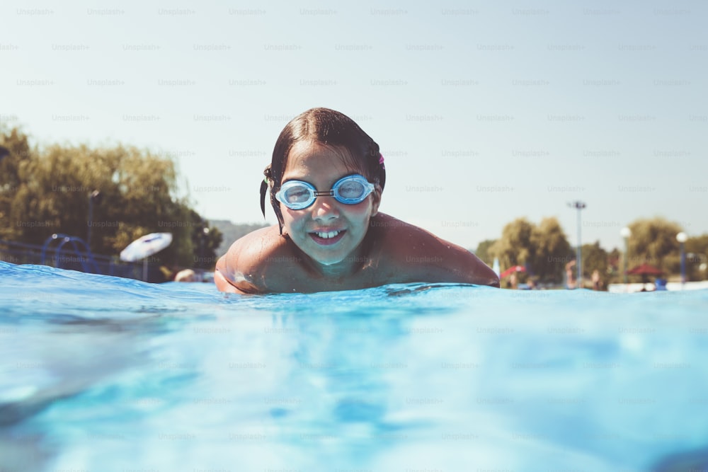 Underwater fun. Cute little girl with goggles swimming underwater and diving in the swimming poll. Sport and leisure.