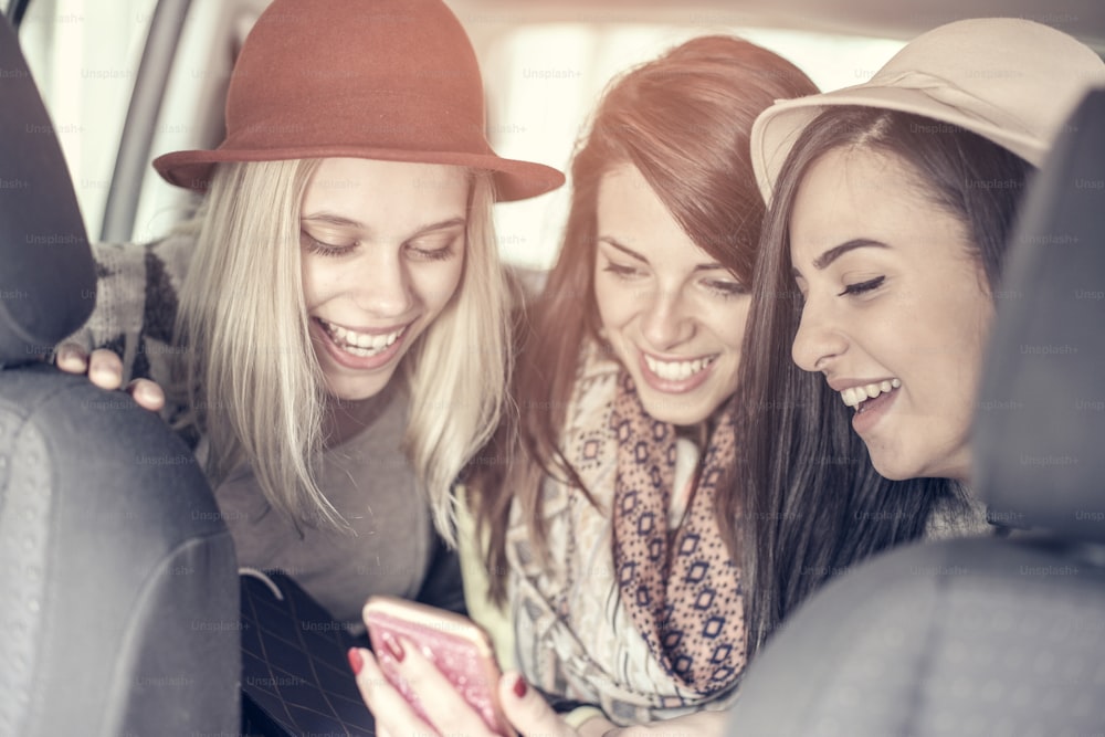 Drei beste Freunde im Auto und fahren lächerliche Nachricht. Mädchen zeigt ihren Freunden Nachrichten.
