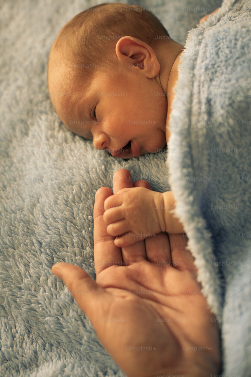 Newborn baby boy holding hand of his mother.