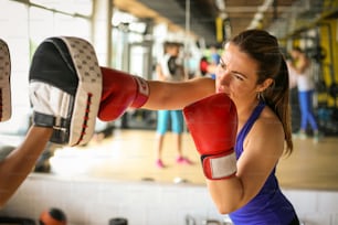 여자 권투 선수가 스파링 파트너의 글러브를 치고 있다. 체육관에서 여자 운동.