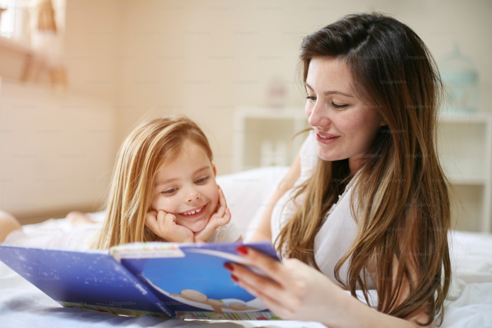 Madre leyendo el cuento a su hija después de despertarse. Madre con su hija disfrutando de la historia.