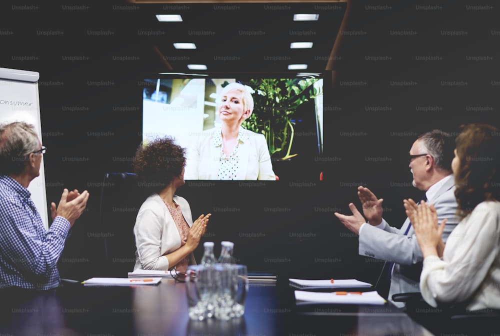 Business people clapping for colleague on video call