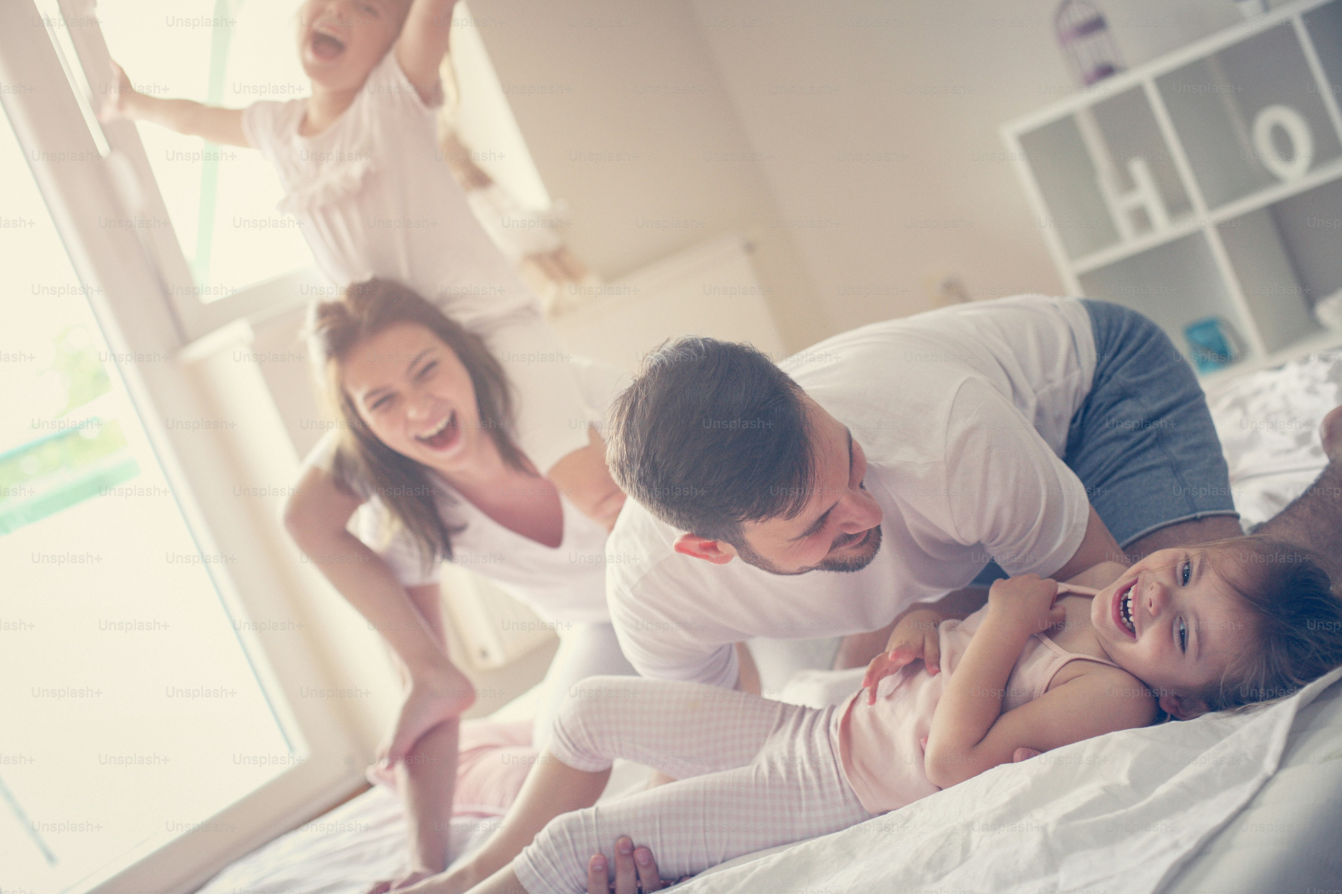 Family spending time at home together. Little girls sitting on mothers shoulders.