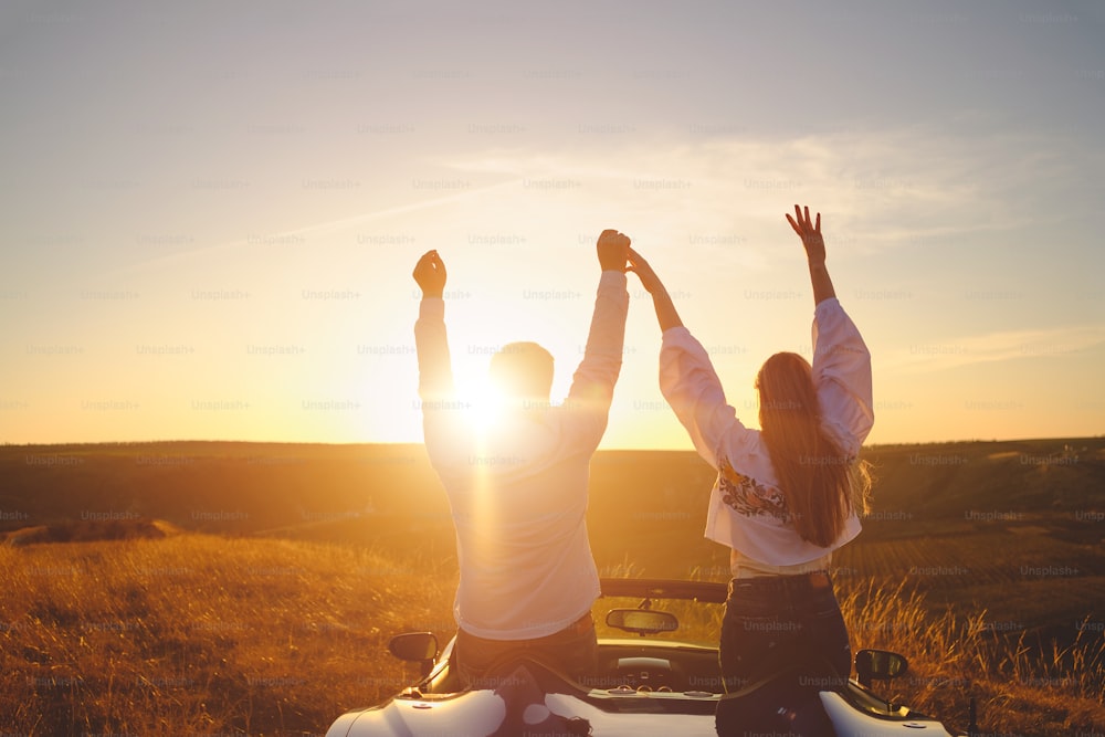 Happiness couple stay in the new sport car hugging and kissing at sunset