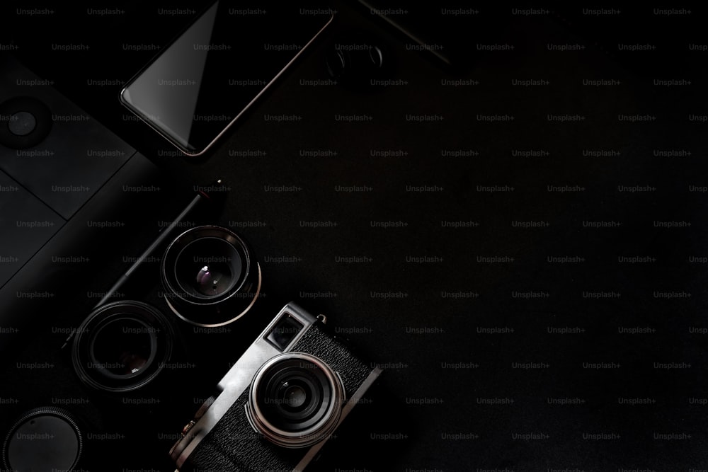 Maquette de bureau design. Bureau, appareil photo - équipement photographique, téléphone intelligent sur table à dessus sombre.