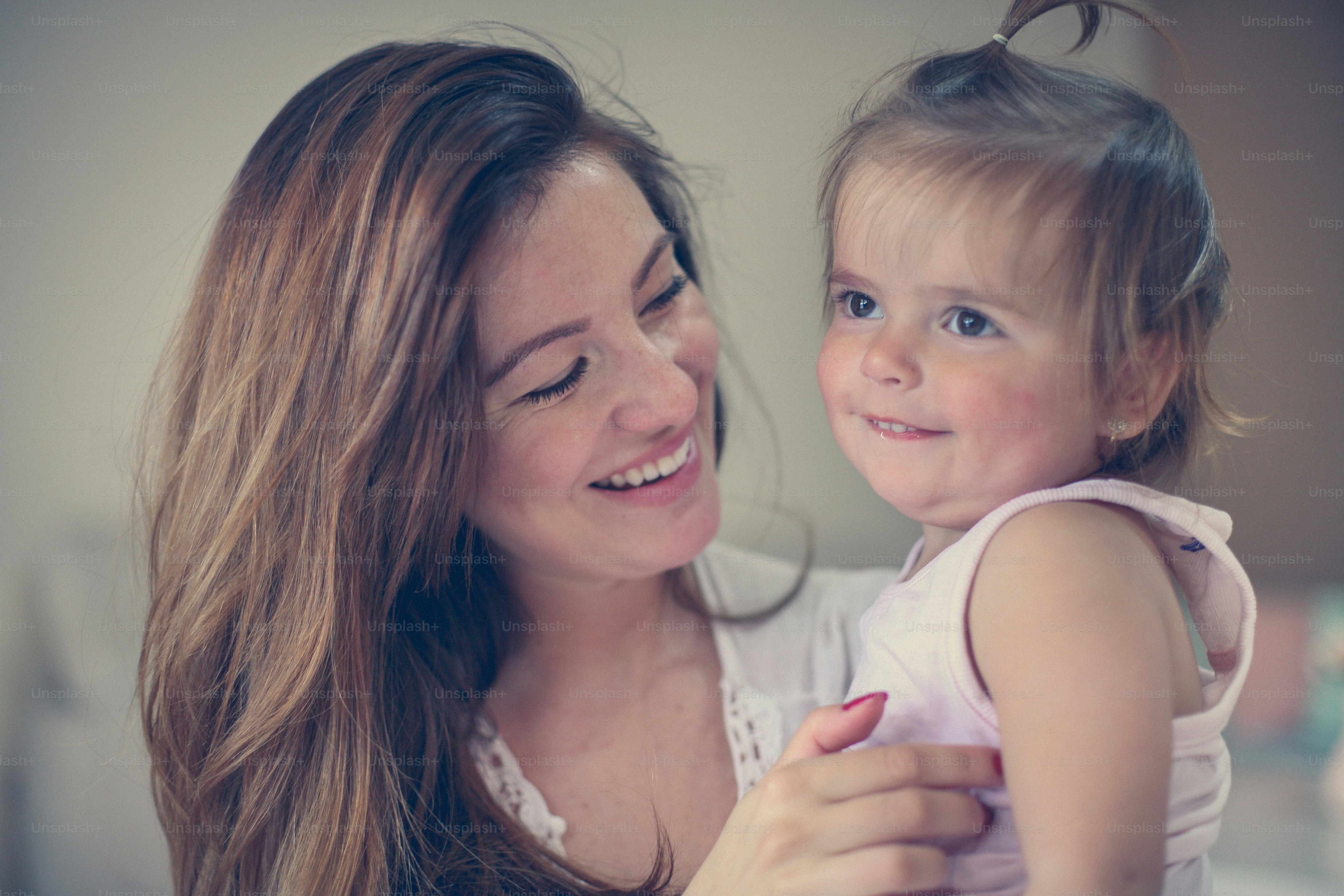 Mother and her cute baby at home. Mother enjoying in free time with her little baby. Mother holding little baby in her arms.
