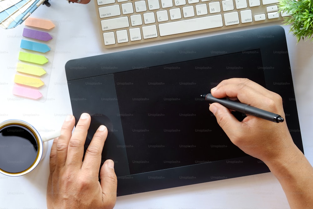 Designer gráfico usando tablet gráfico para fazer seu trabalho na mesa