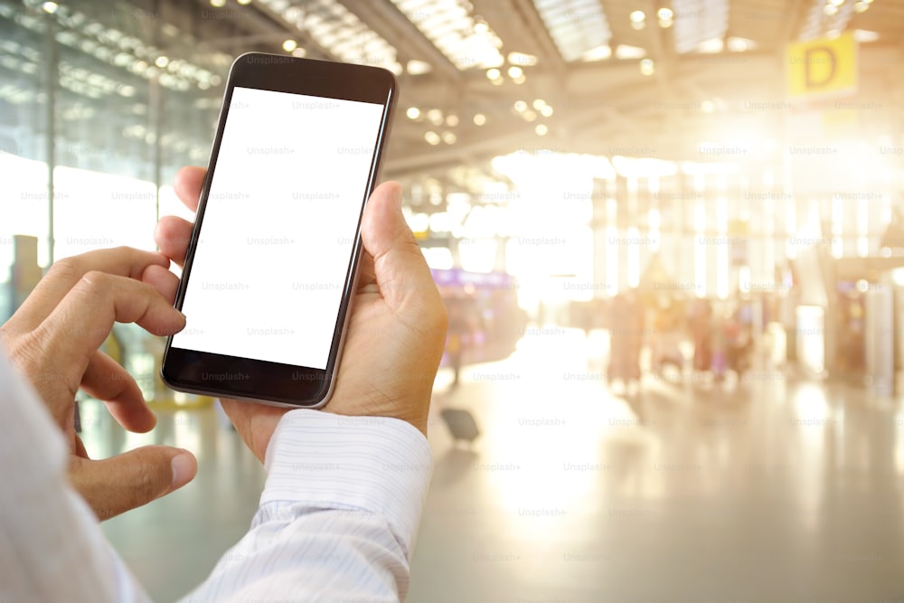 Man hands holding blank screen smartphone in terminal airport.