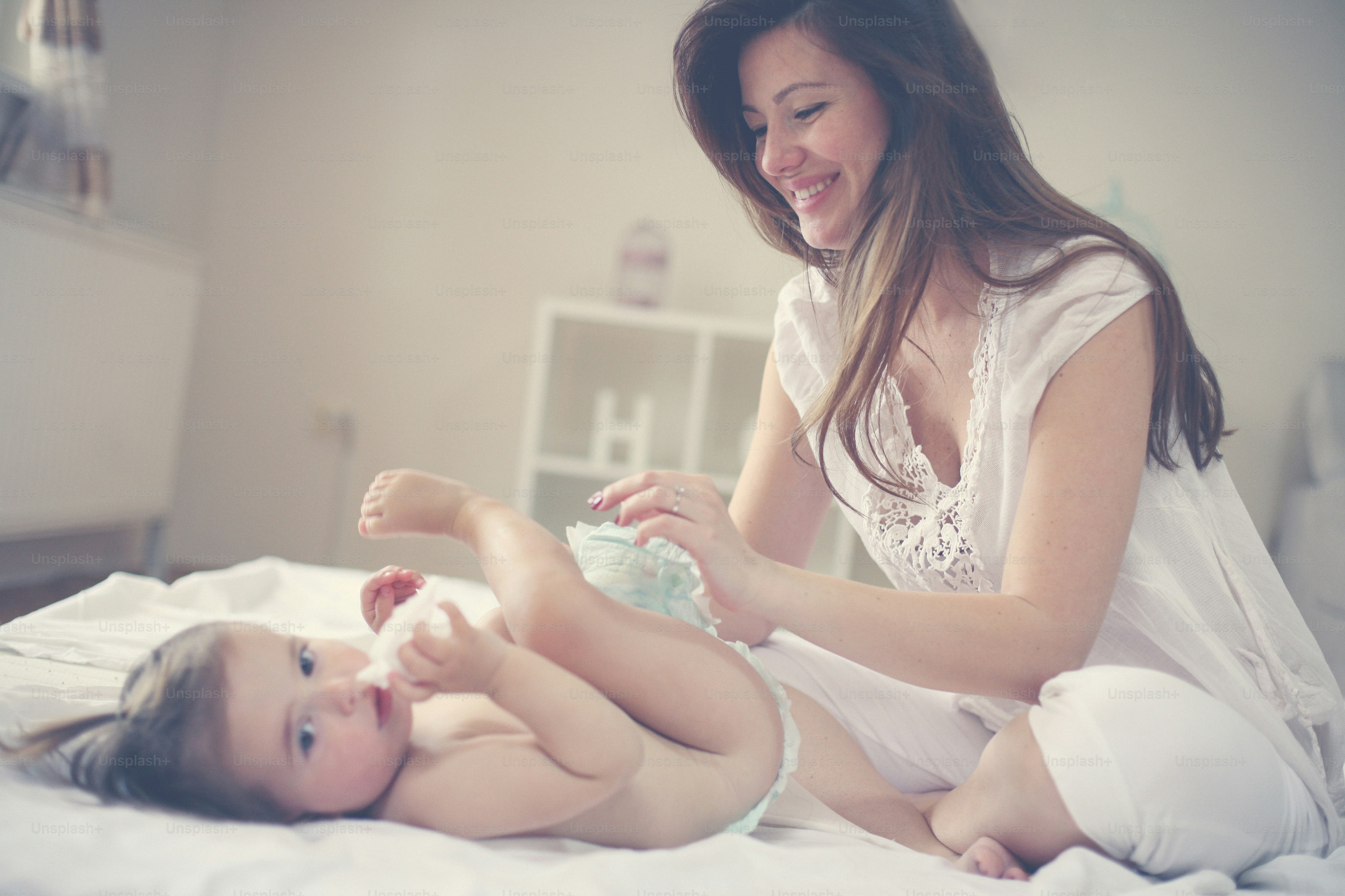 Foto Madre con su bebé en casa. Madre cambiando pañales a su pequeño ...