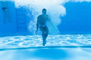 Divertimento subacqueo. Giovane bell'uomo che nuota sott'acqua e si tuffa nel sondaggio di nuoto. Sport e tempo libero.