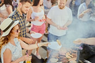 Grupo de amigos comiendo, bebiendo, bailando y pasando un buen rato en una fiesta al aire libre