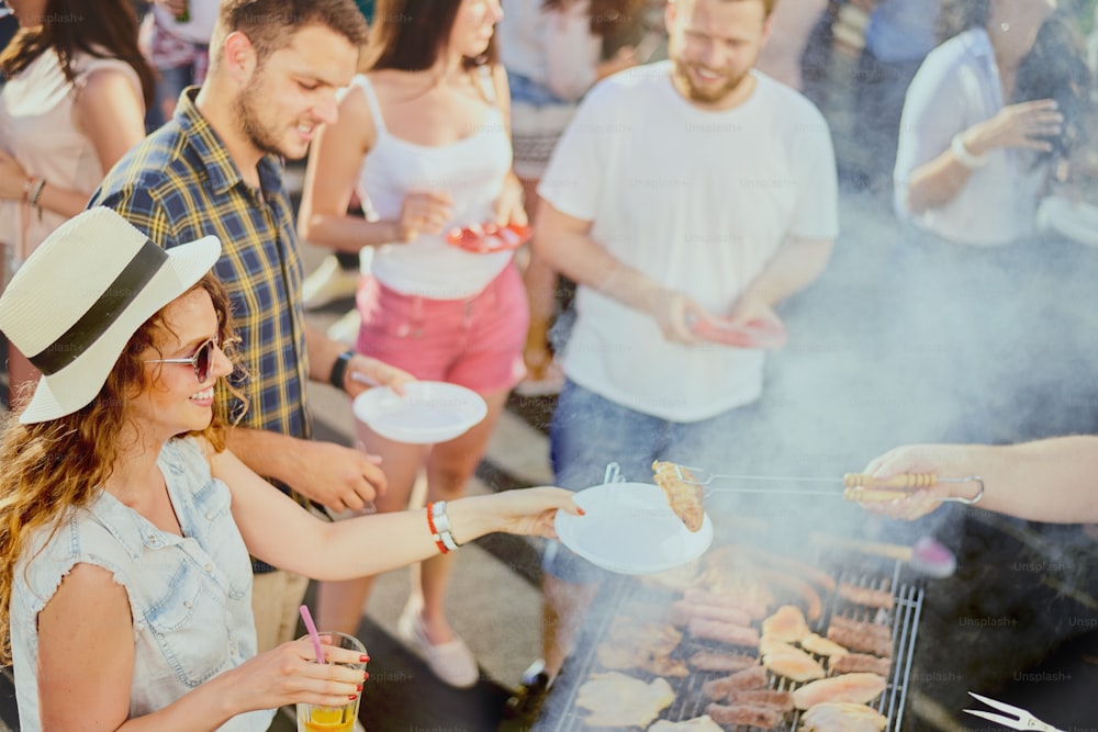 Gruppo di amici che mangiano, bevono, ballano e si divertono alla festa all'aperto