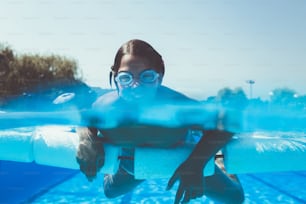 Divertimento subacqueo. Bambina carina con occhialini che nuota sott'acqua e si tuffa nel sondaggio di nuoto. Sport e tempo libero.