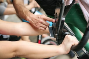 Nahaufnahme der Hände der Menschen. Personal Trainer ändert die Geschwindigkeit des Fahrrads." n