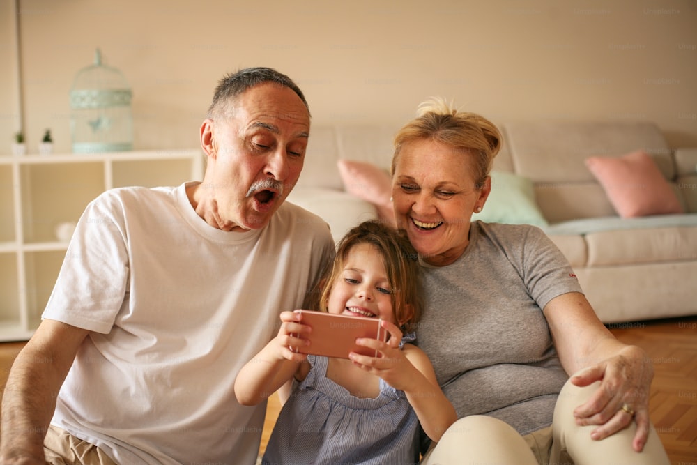 Grandmother and grandfather with their granddaughter making self-picture together.