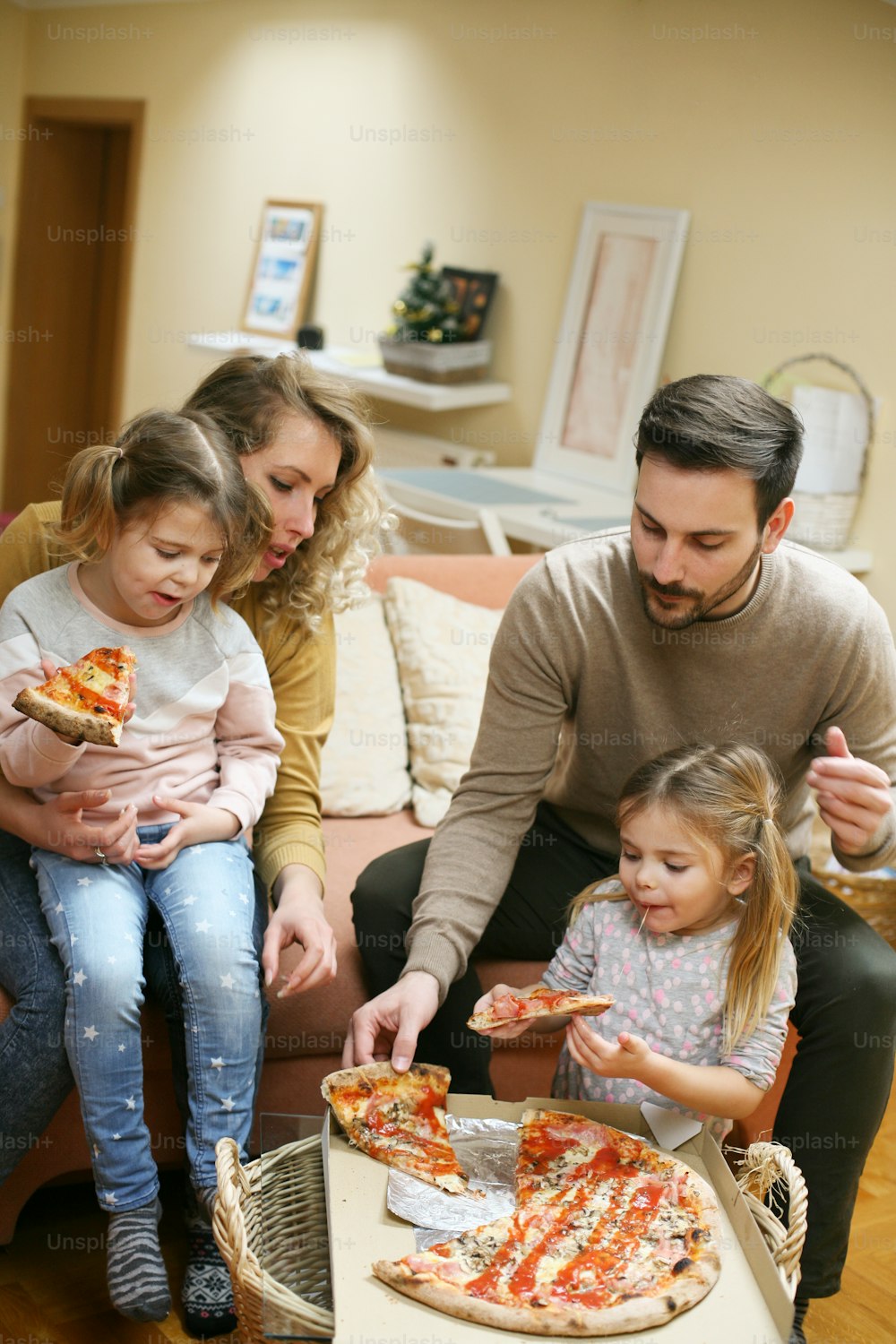 Pais e filhos comendo pizza juntos. Família feliz desfrutando em refeição juntos em casa.