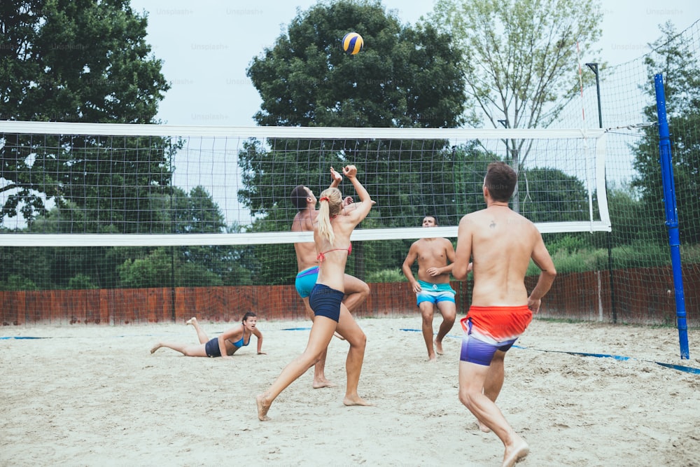 Gruppo di giovani che giocano a beach volley in una bella giornata di sole.