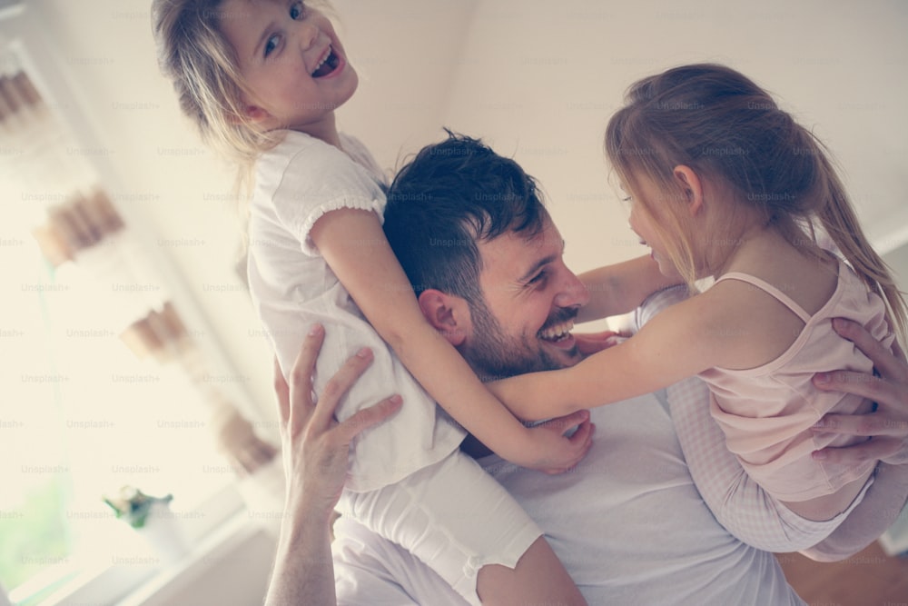 家で過ごす幸せな父と小さな娘。家で遊ぶ父と娘。父親の肩に座っている小さな女の子。