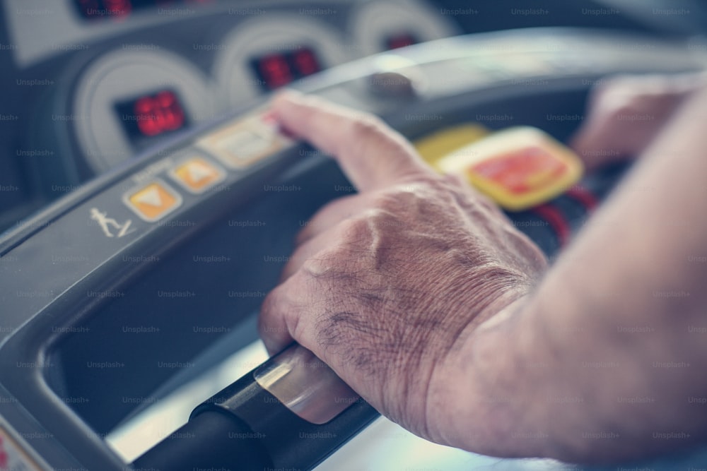 Close up. Active senior woman typing speed on exercise machine. Woman workout in gym.