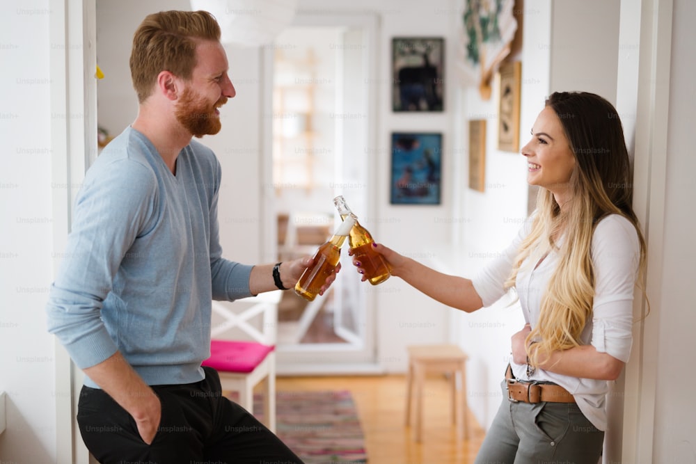Happy couple in love drinking beer and toasting at home