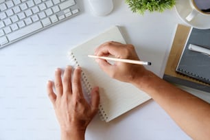 Man writing  notebook or working on white desk workspace office table.