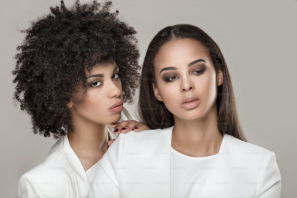 Zwei elegante junge afroamerikanische Frauen posieren zusammen.