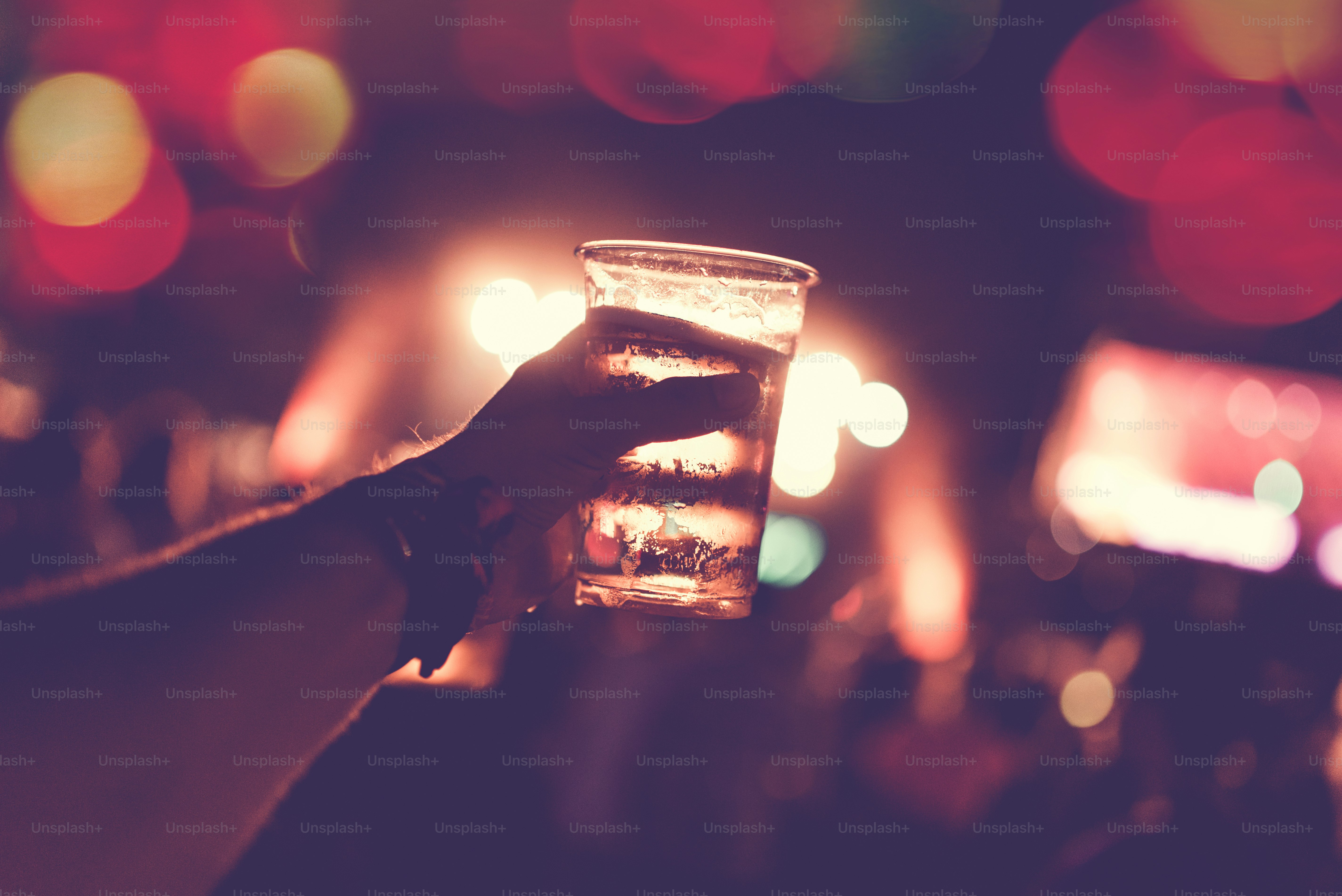 Silhuetas da multidão de concertos do festival em frente às luzes brilhantes do palco. Pessoas irreconhecíveis e efeitos coloridos.