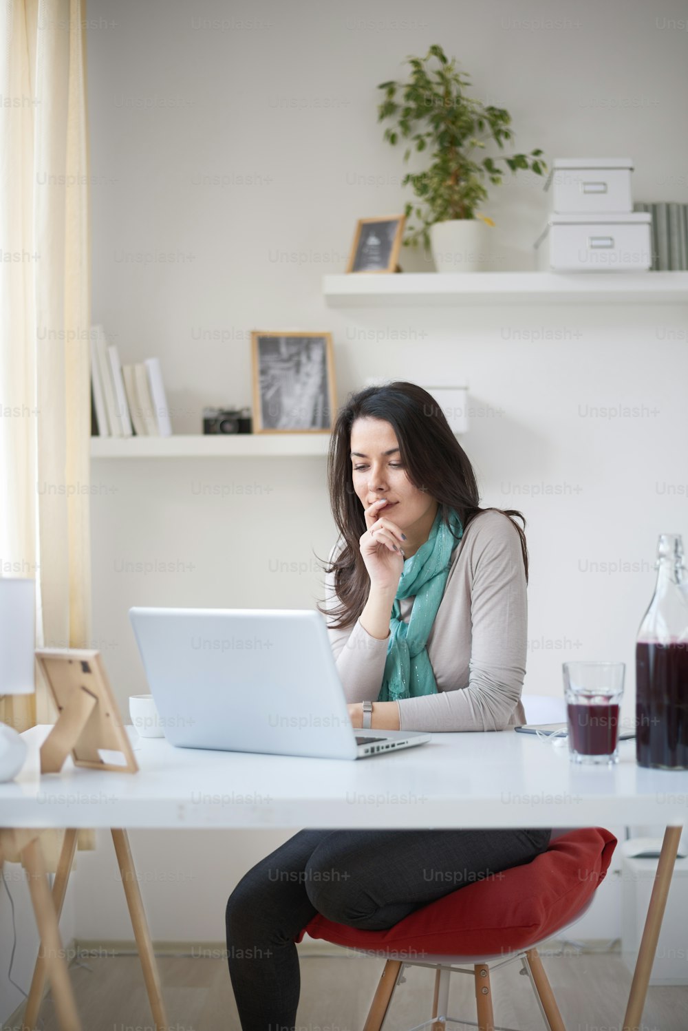 Caucasian woman using laptop in home office and drinking coffee