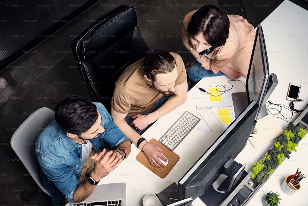 Top view serious men and serene woman having job on computer in cozy office