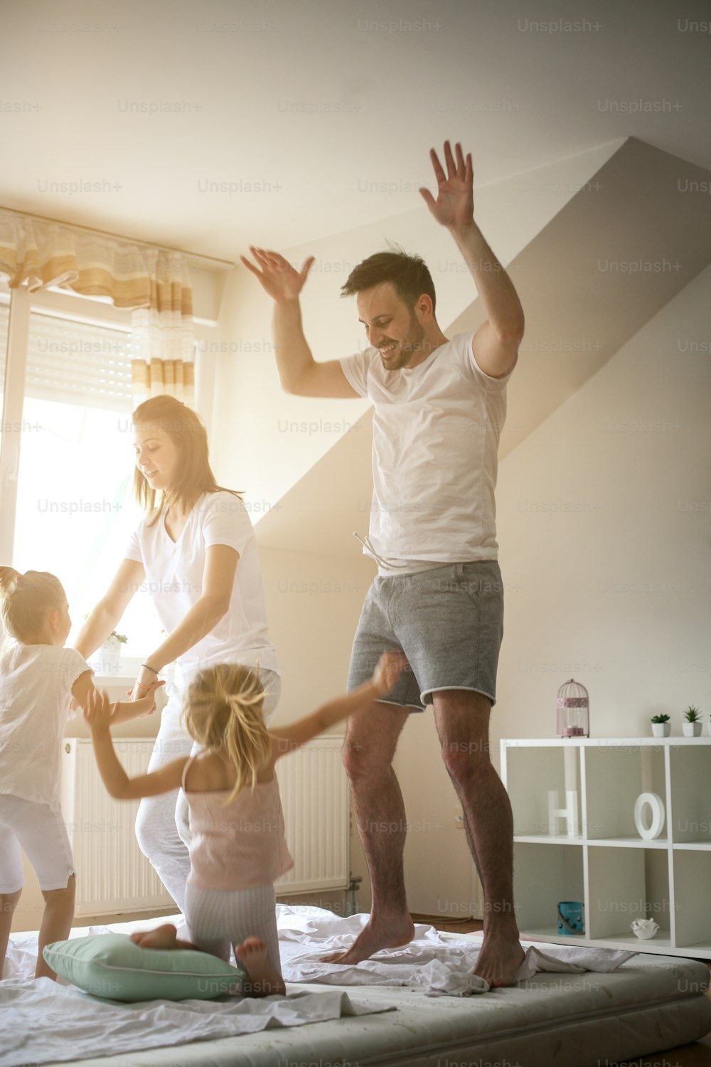 Family spending free time at home. Happy family jumping on bed together.