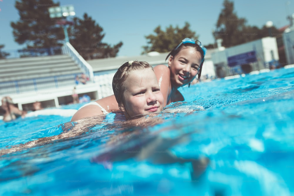 Underwater fun. Two cute little girl with goggles swimming underwater and diving in the swimming poll. Sport and leisure.