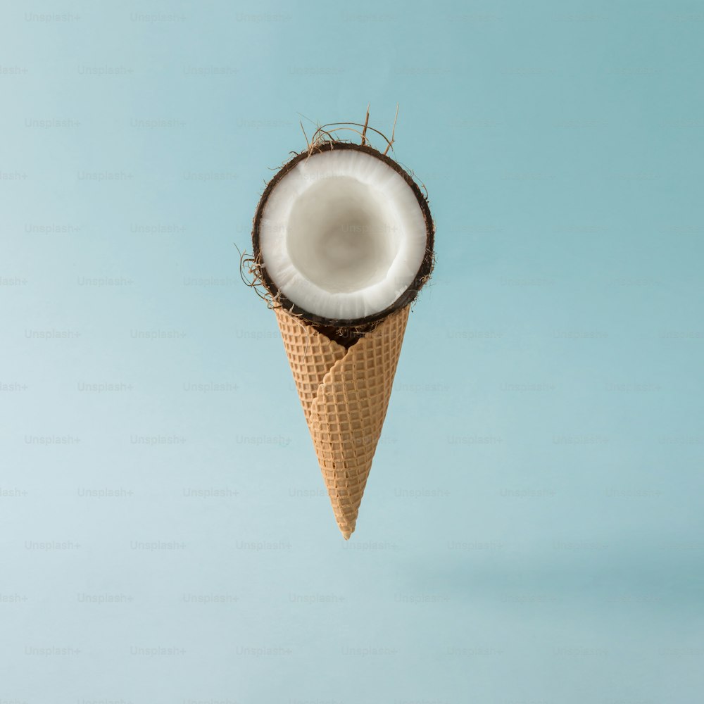 Coconut with ice cream cone on pastel blue background. Foos creative concept.
