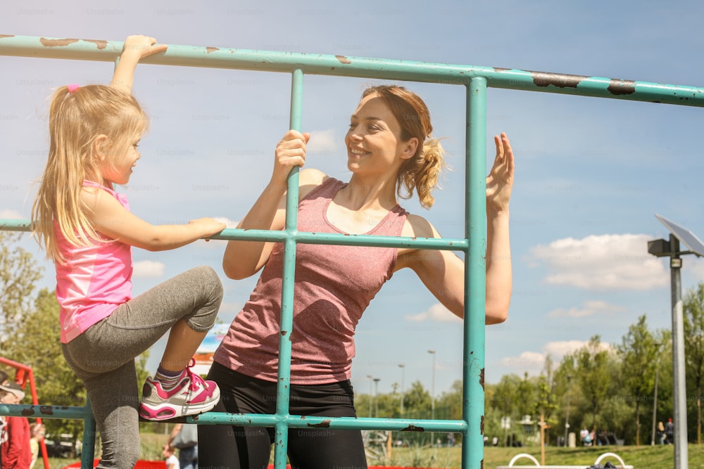 Mother and daughter playing in the playground. Mother with his little girl enjoying in beautiful spring day.