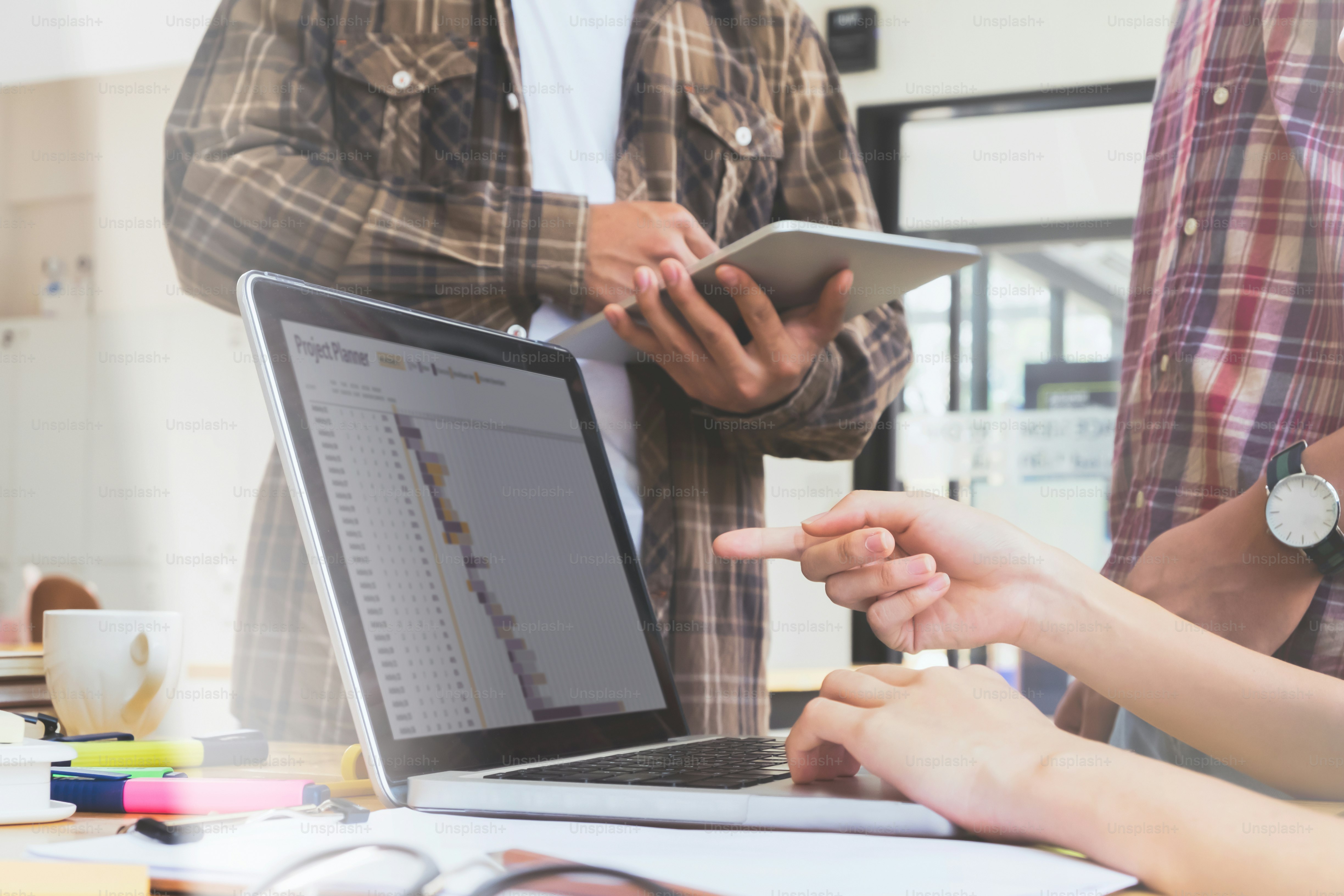 Des personnes qui collaborent sur un plan de projet sur un ordinateur portable dans un bureau lumineux
