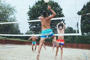 Grupo de jóvenes jugando voleibol de playa en un hermoso día soleado.