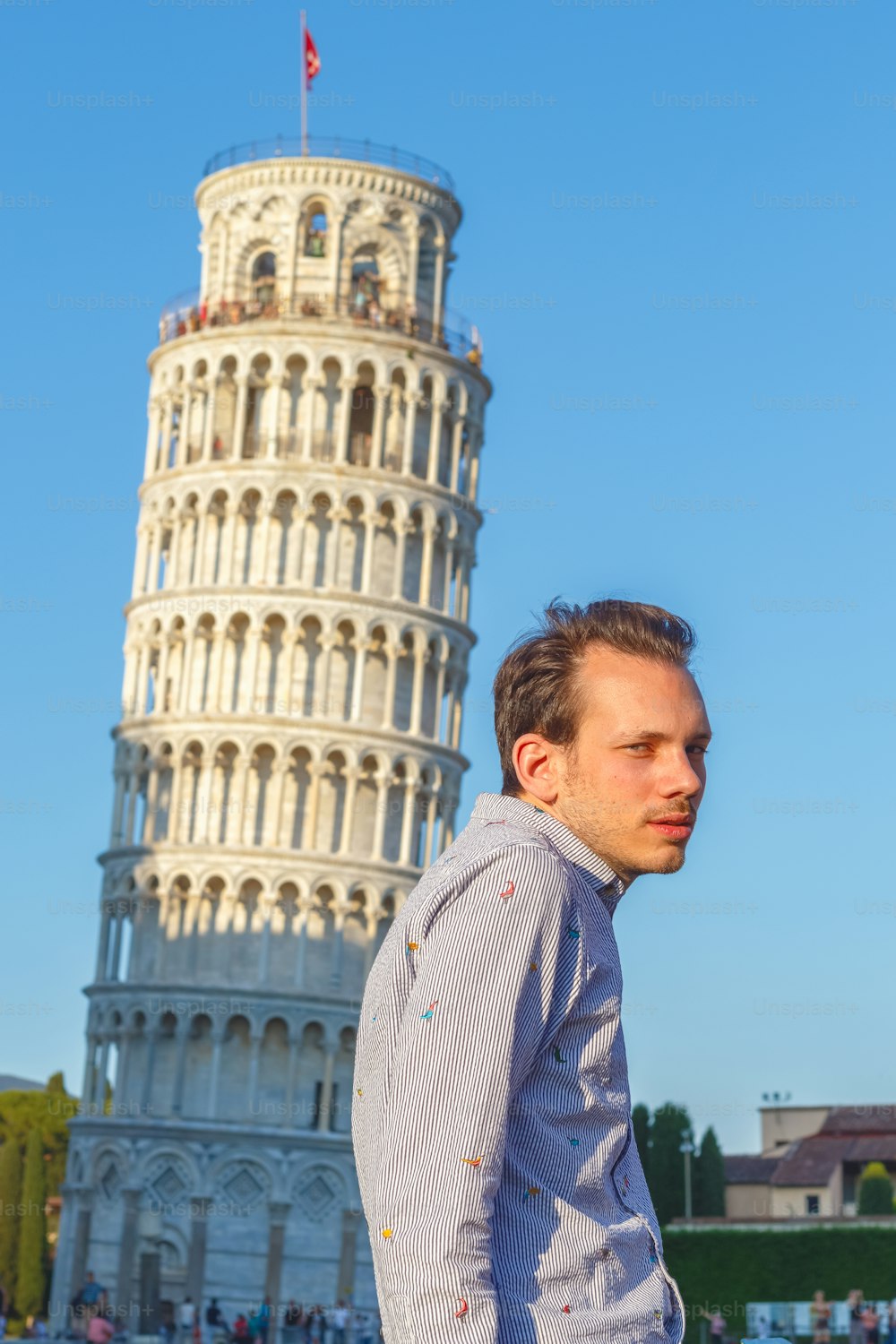 A white young man poses in front of the Leaning Tower in Pisa, Italy