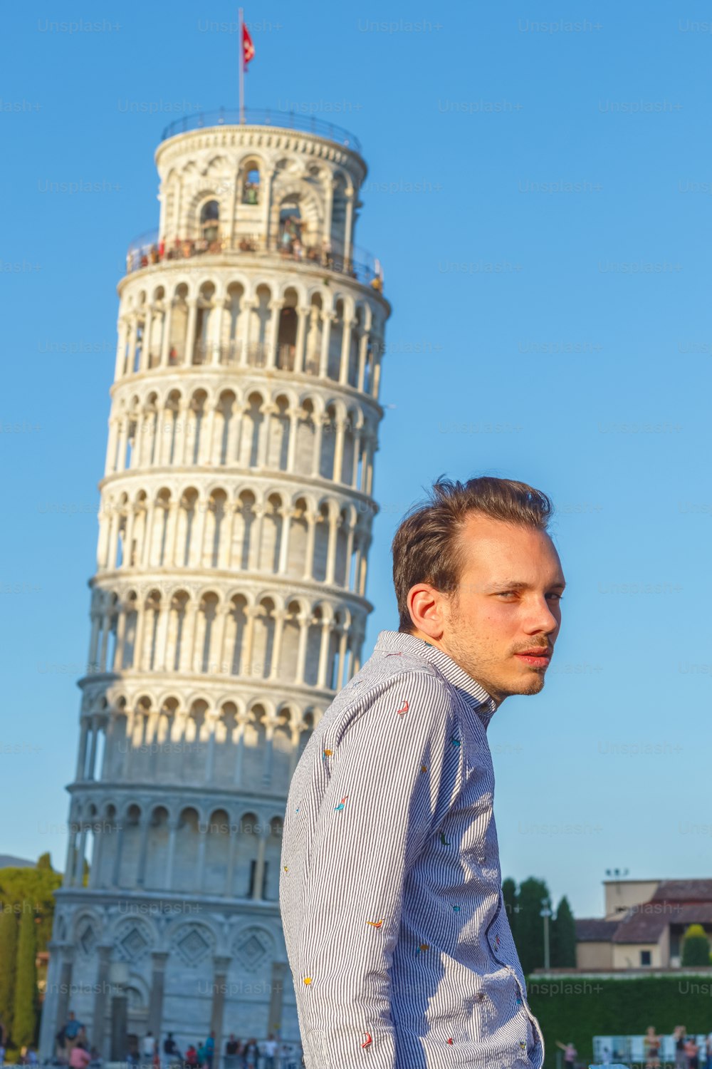 イタリア・ピサの斜塔の前でポーズをとる白人青年