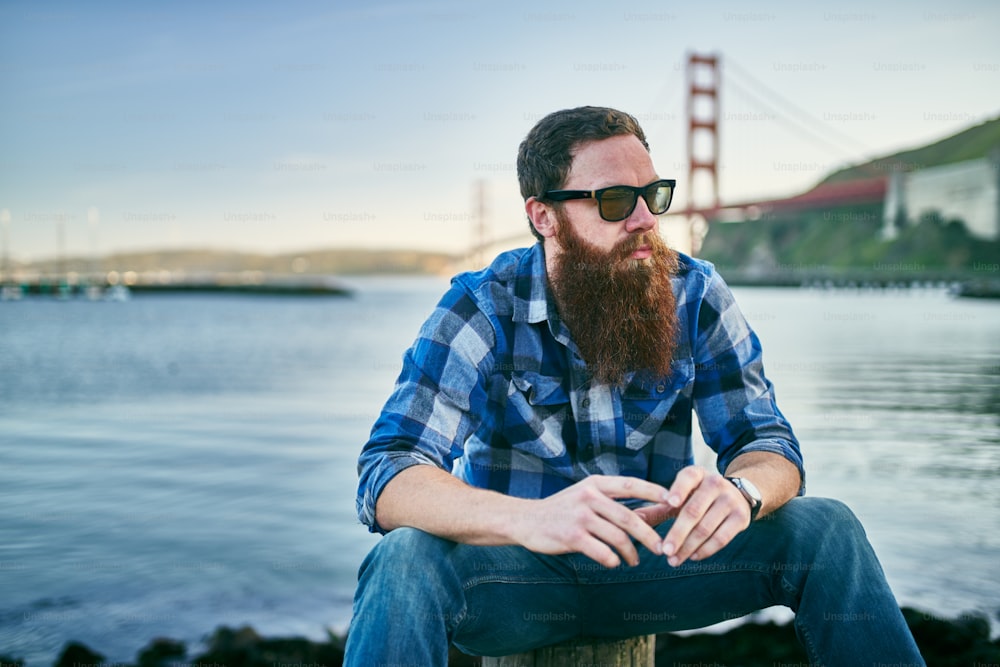 hipster barbudo frio relaxando pela baía em frente à ponte do portão dourado em São Francisco