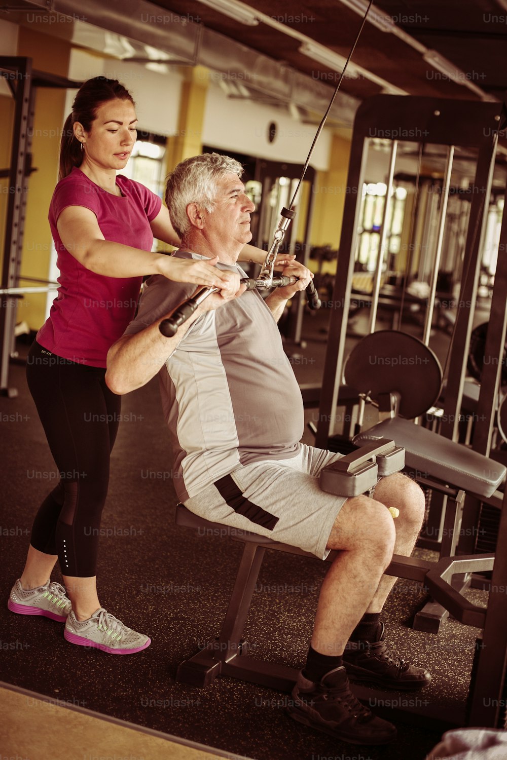 Personal Trainer Arbeitsübung mit Senior Mann im Fitnessstudio.