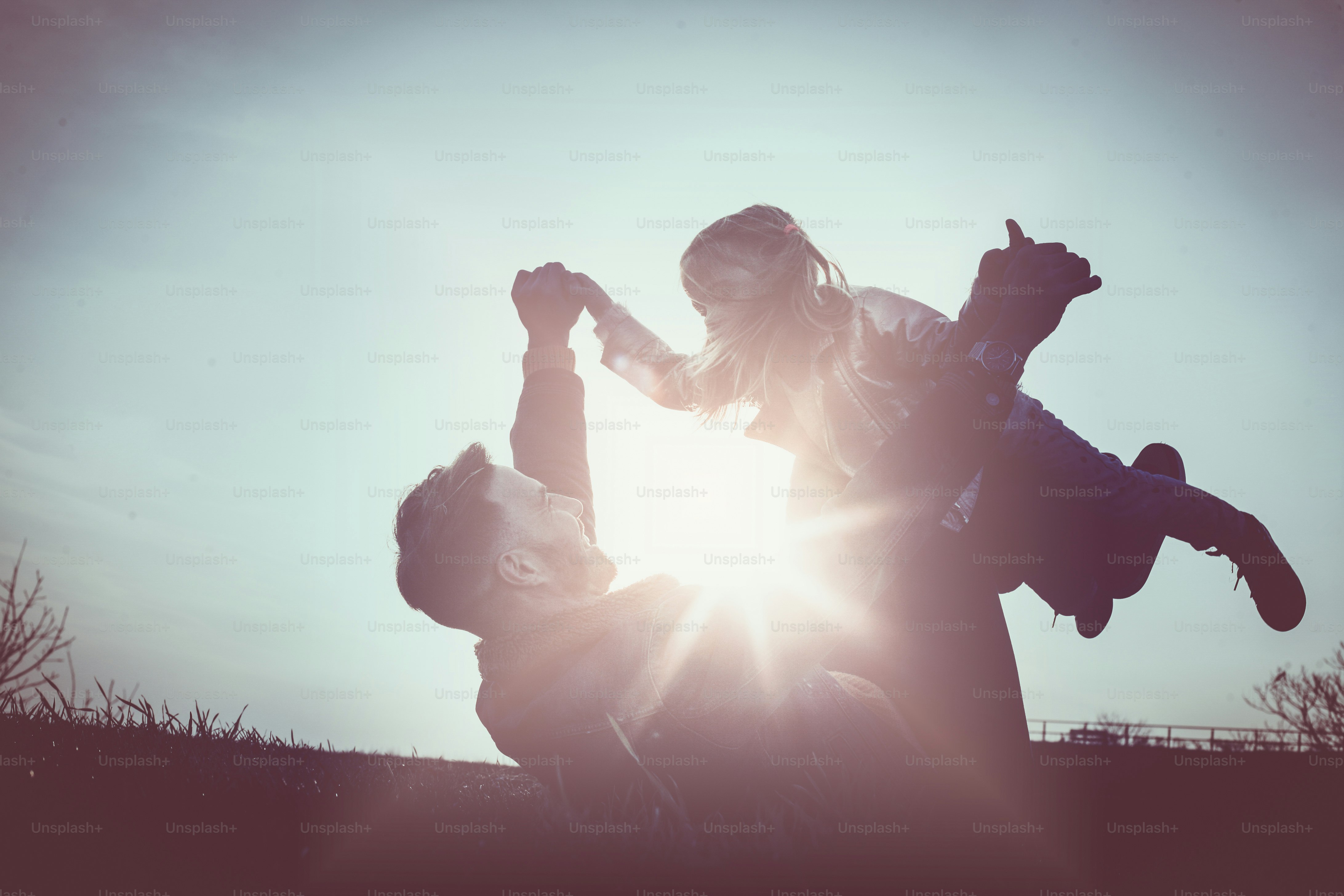 Ayah yang bahagia bermain dan berbaring di rumput bersama putrinya. Gadis kecil berbaring di kaki ayah.