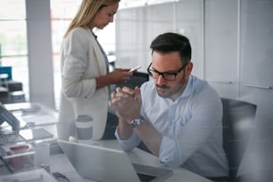 Two business people watching something on laptop. Business woman showing something to colleague in laptop.