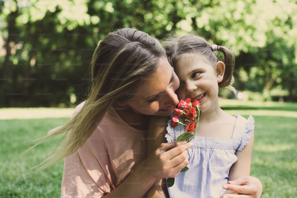 La figlia ha scelto un fiore per sua madre". nGirl dà alla madre l'odore di un fiore che è stato colto.