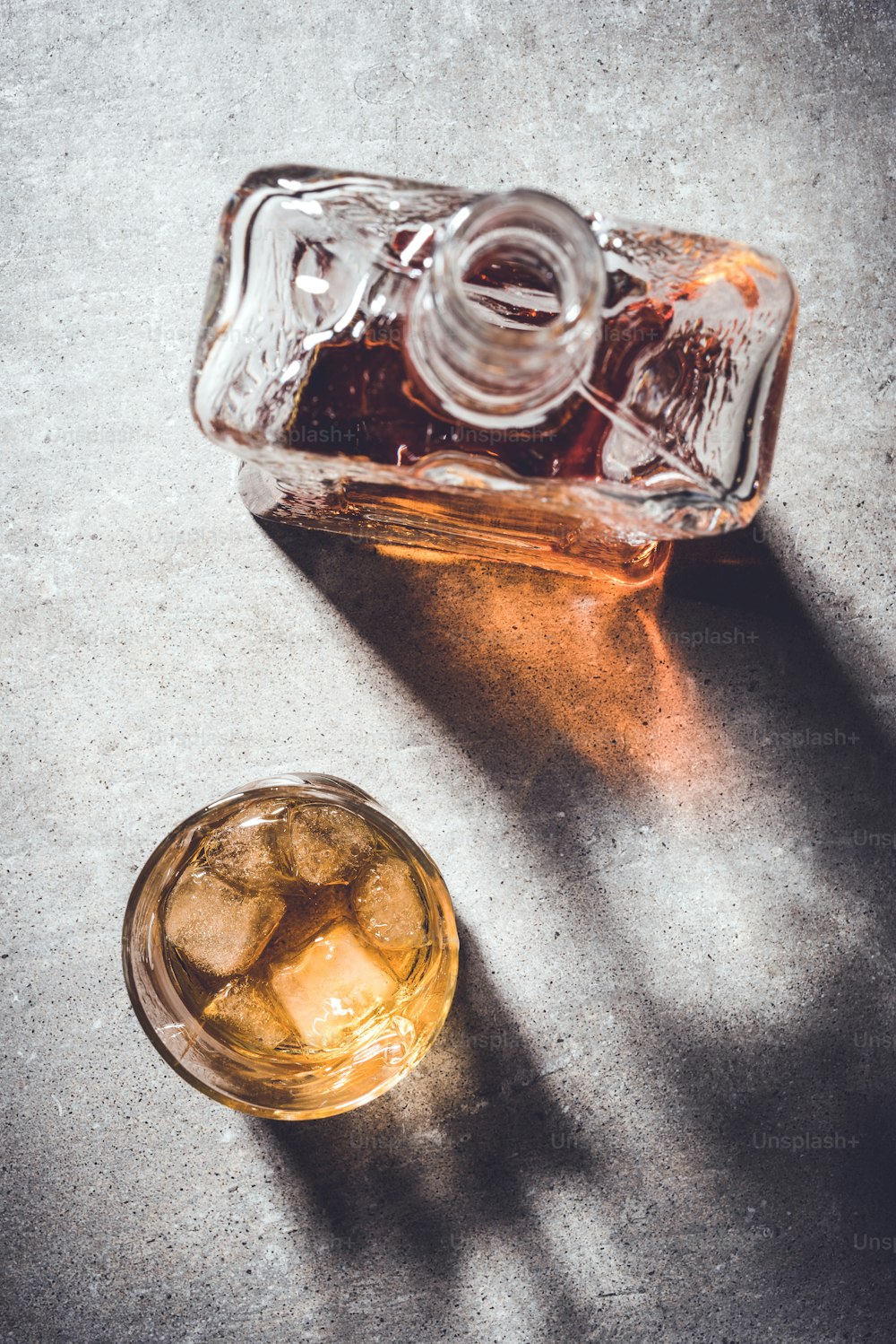 Bottiglia di whisky e bicchiere di whisky su tavolo di pietra grigia. Primo piano