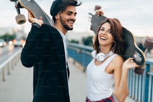 Immagine di giovane coppia attraente che trasporta skateboard e si diverte