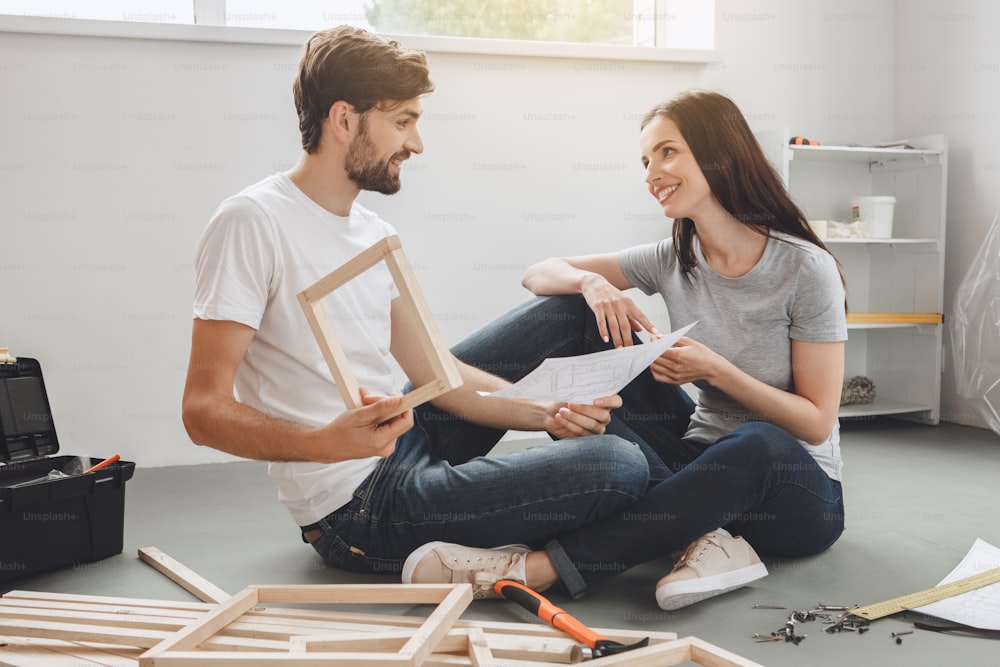 Young man and woman doing apartment repair together looking on plan