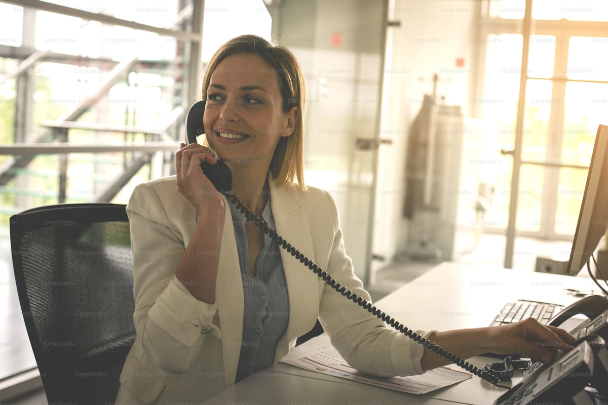 Business woman working in office, talking on landline phone