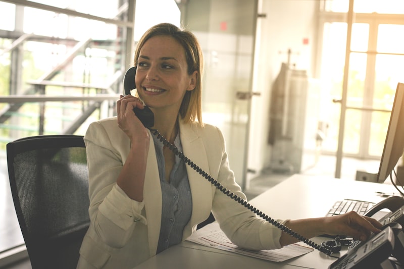 Business woman working in office, talking on landline phone