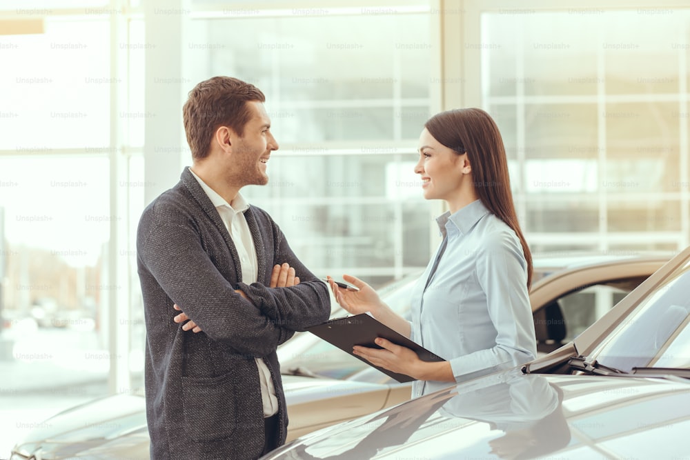 Jeune homme et femme dans un service de location de voitures signant un contrat