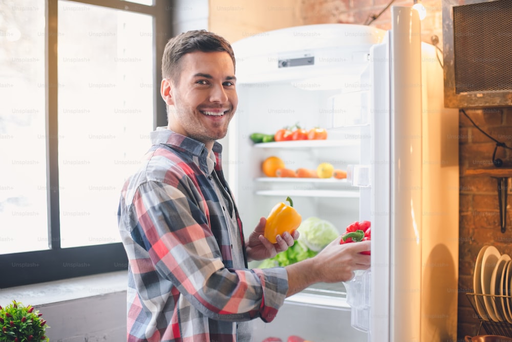 Young man vegan put purchases healthy products in refrigerator